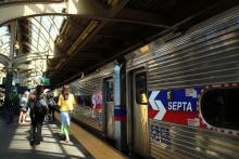 A SEPTA Train pulling up to a station with a few people waiting.